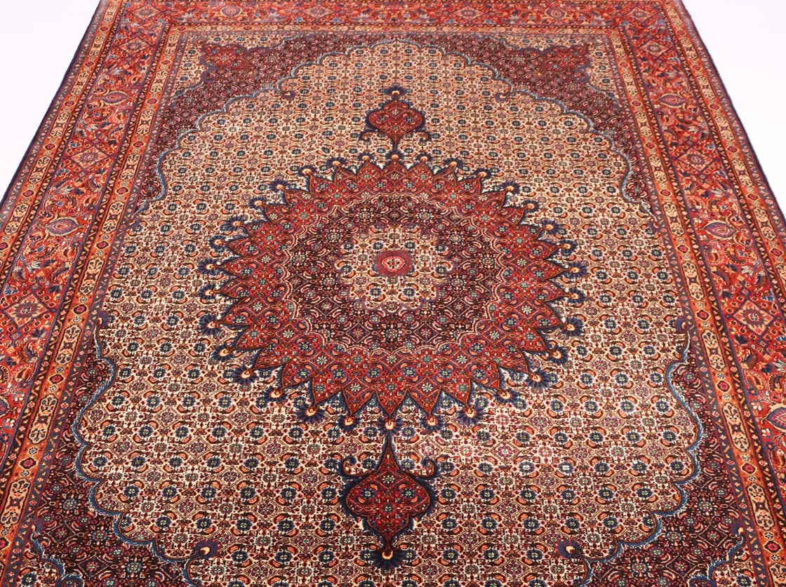 A close-up photo of a Persian rug with a fish motif design. The rug has a cream-colored background with various shades of blue and green used for the fish design.