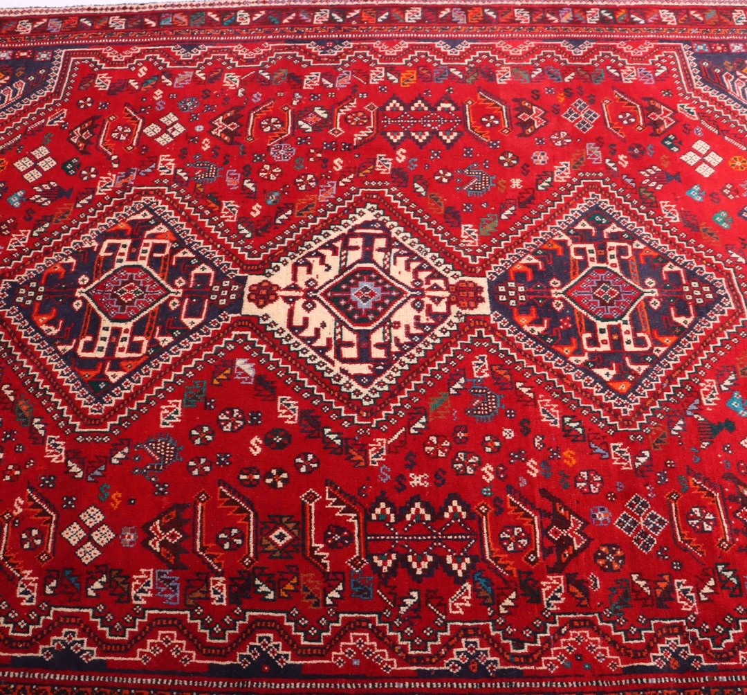 Close-up of a bold and colorful Shiraz rug, featuring intricate geometric designs in shades of red, blue, and cream.
